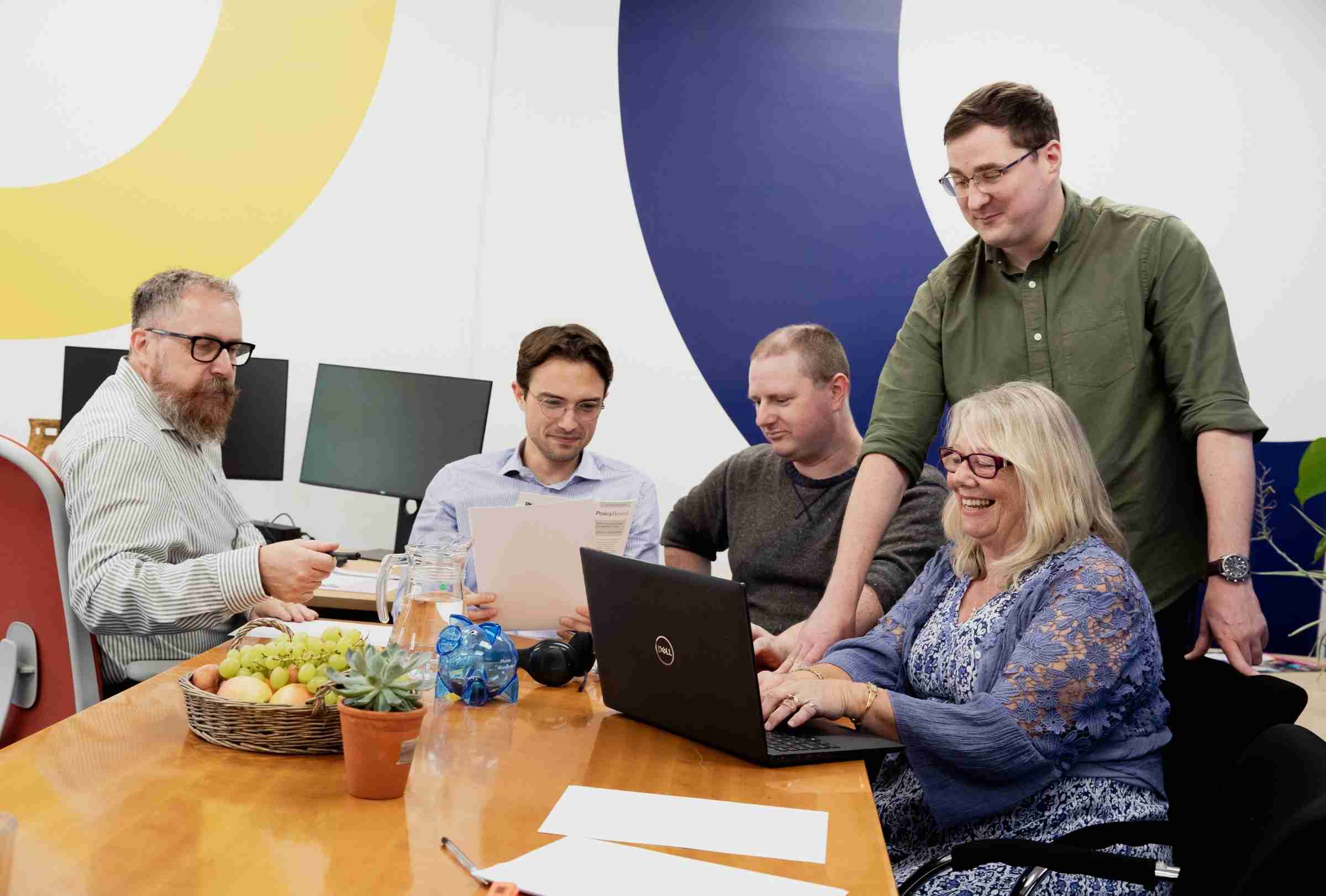 Photo Of GWCU Finance Team Working Together At A Table With Laptops And Papers