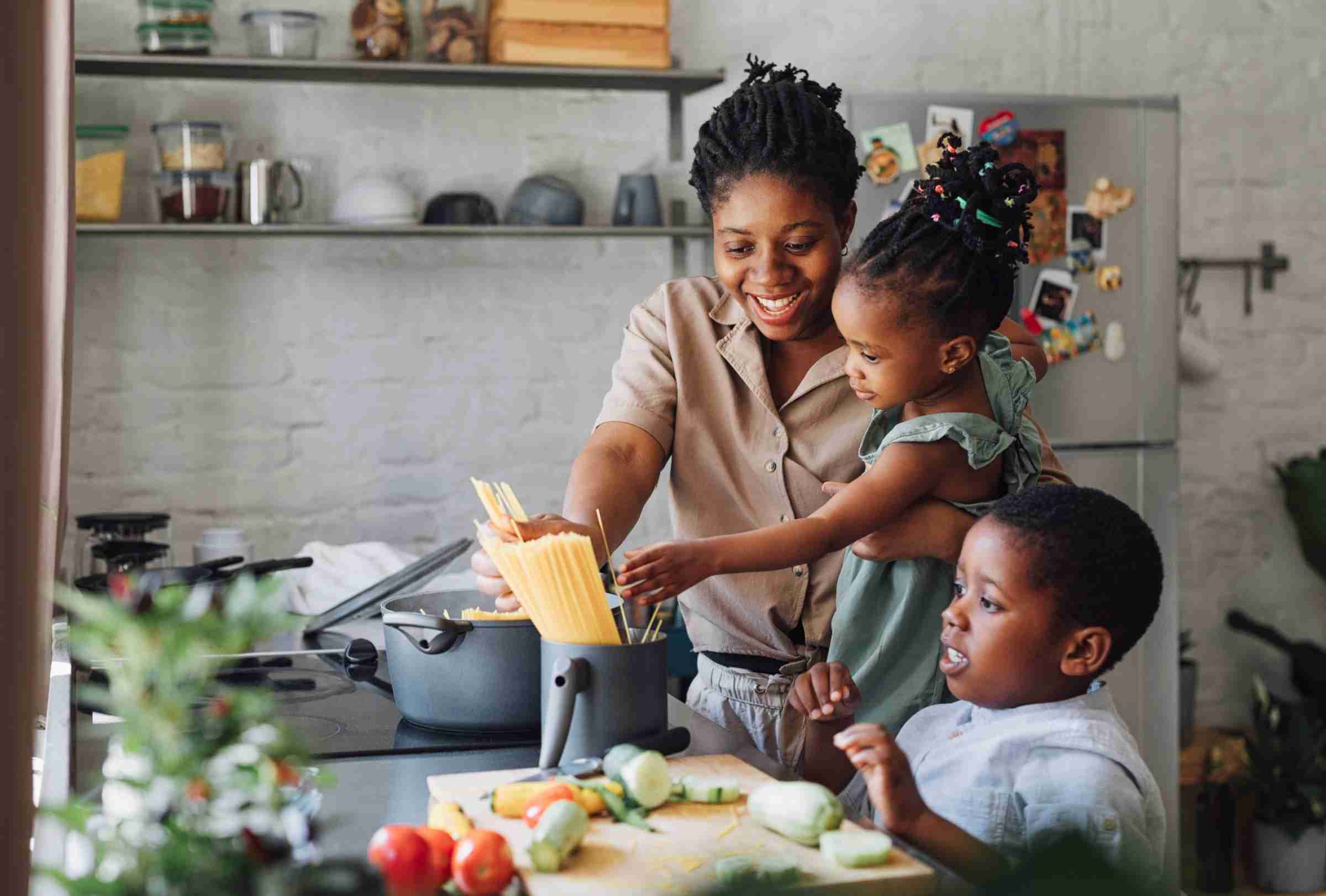 Mother Cooking Spaghetti With Two Children