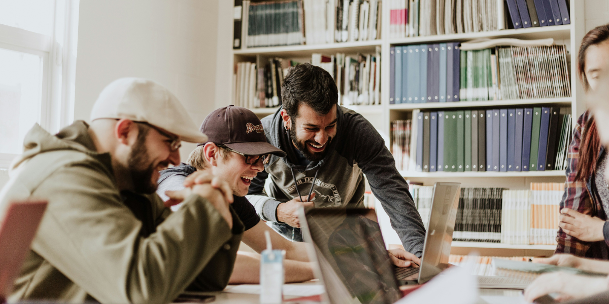people gathered around a table laughing at laptops