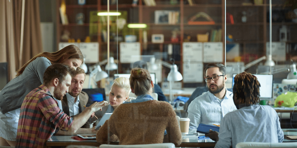a group of employees sitting at a table in a glass room